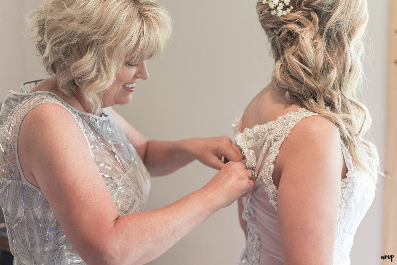 Bride's mother helping her do up the wedding dress