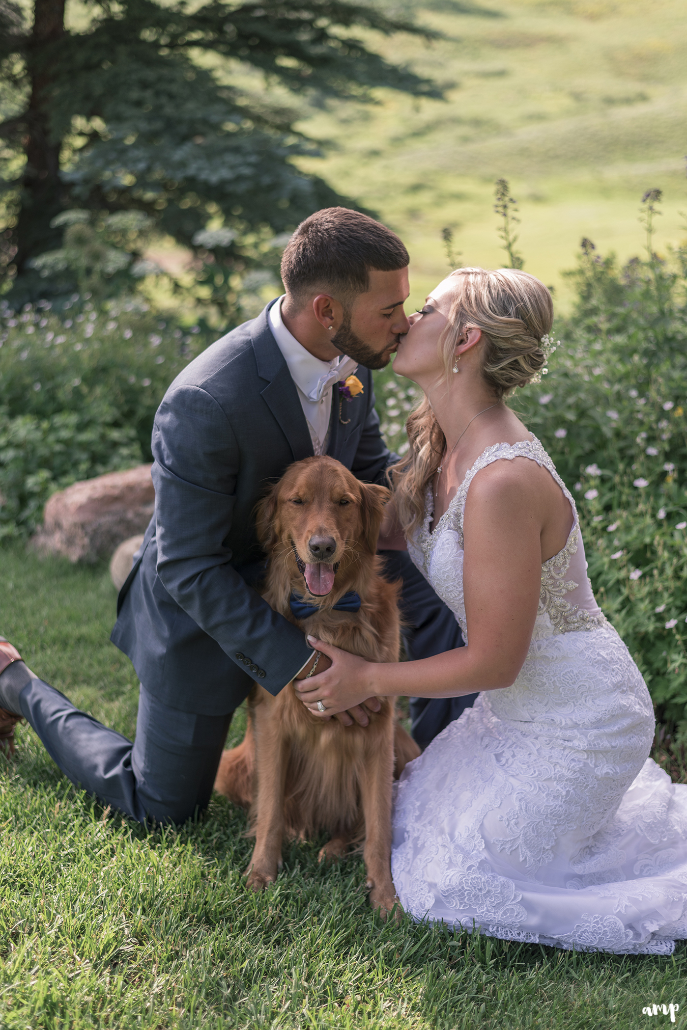 Bride and groom share a kiss over their dog