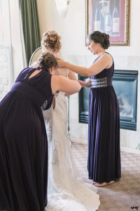 Bridesmaids helping the bride get dressed