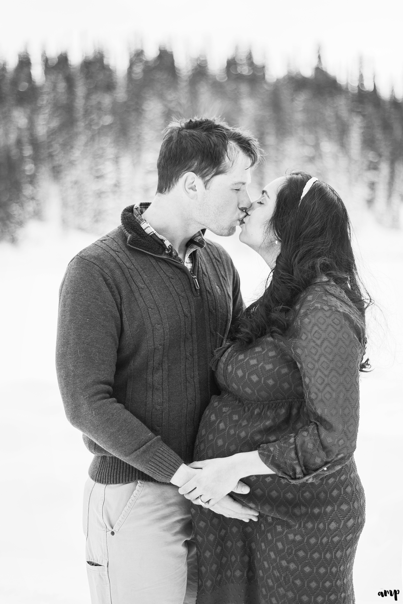 Black and white photo of expecting couple kissing at Mesa Lakes